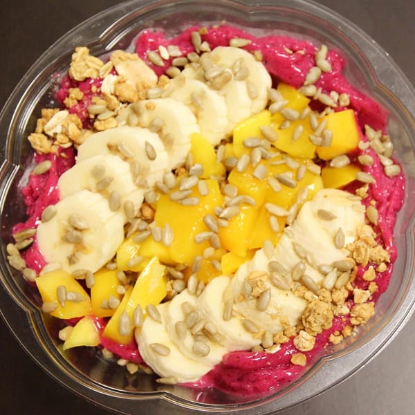 A vibrant Jungle Bowl with dragon fruit base, topped with bananas, mango, granola, and sunflower seeds.