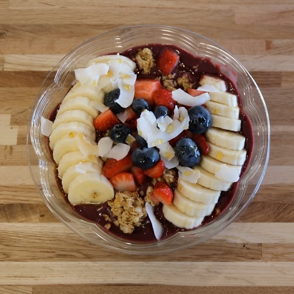 A Jungle Bowl acai bowl with bananas, blueberries, strawberries, granola, and coconut flakes.